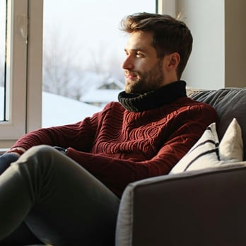 man sat inside warm with cold weather outside-1