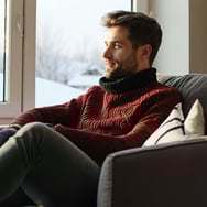 man sat inside warm with cold weather outside-1